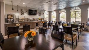 uma sala de jantar com mesas, cadeiras e janelas em Best Western Plus Heritage Inn Houston em Houston