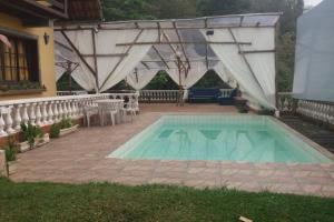 a swimming pool in a yard with a patio at Casa com Piscina e Churrasqueira Perto da CBF, Feirarte, Parque Nacional in Teresópolis