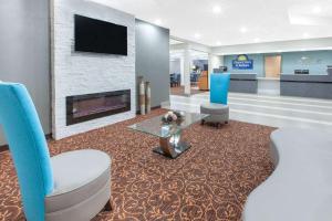 a hotel lobby with a fireplace and two chairs at Days Inn & Suites by Wyndham Grand Rapids Near Downtown in Grand Rapids