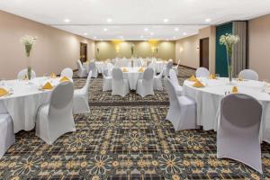 a large banquet room with white tables and chairs at Days Inn & Suites by Wyndham Grand Rapids Near Downtown in Grand Rapids