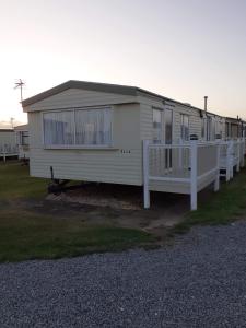 a white mobile home with a porch and a fence at Golden Sands Ingoldmells (Atlantis) in Skegness