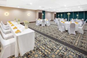 un salón de banquetes con mesas blancas y sillas blancas en Baymont by Wyndham Grand Rapids Near Downtown, en Grand Rapids