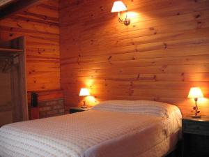 a bedroom with wooden walls and a bed with two lamps at Cabañas Lorien in Esquel