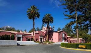 a pink house with palm trees in front of a street at Wyndham Costa del Sol Arequipa in Arequipa