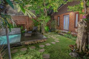 einen Garten mit einem Pool, einem Stuhl und Bäumen in der Unterkunft Tirta Bali Villa in Jimbaran