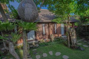 ein Backsteinhaus mit Bäumen davor in der Unterkunft Tirta Bali Villa in Jimbaran