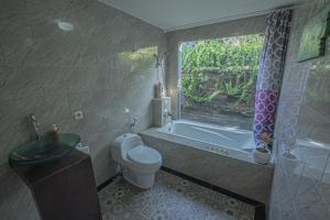 ein Badezimmer mit Badewanne und Toilette und einem Fenster in der Unterkunft Tirta Bali Villa in Jimbaran