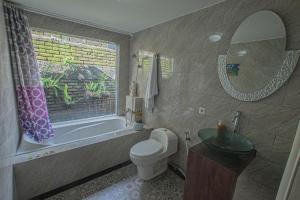 ein Badezimmer mit Badewanne, Toilette und Waschbecken in der Unterkunft Tirta Bali Villa in Jimbaran