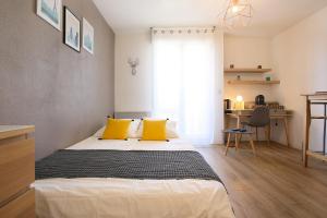 a bedroom with a bed with yellow pillows and a desk at expat renting - Le Sophia - Casino Barrière - Parking in Toulouse