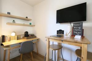 a room with a desk with a television on a wall at expat renting - Le Sophia - Casino Barrière - Parking in Toulouse