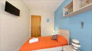 a small bedroom with an orange bed with a television at Sabbia e Mare in Torre San Giovanni Ugento