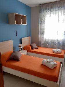 a bedroom with two beds with orange sheets and a window at Sabbia e Mare in Torre San Giovanni Ugento