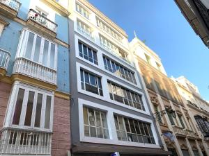 un gran edificio blanco con ventanas en una calle en El mirador de Ancha, en Cádiz