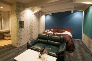 1 dormitorio con sofá de cuero y cama en Hotel JuJu, en Kurume