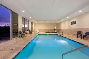 a pool in a hotel room with chairs and a table at La Quinta by Wyndham Morgan Hill-San Jose South in Morgan Hill
