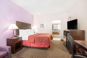 a hotel room with a bed and a flat screen tv at Days Inn by Wyndham Bryan in Bryan