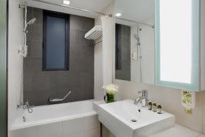 a bathroom with a sink and a tub and a mirror at Citadines Xinghai Suzhou in Suzhou