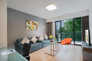 a living room with a blue couch and orange chairs at Citadines Xinghai Suzhou in Suzhou