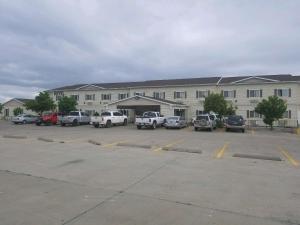 een groot gebouw met auto's geparkeerd op een parkeerplaats bij FairBridge Inn & Suites Williston in Williston