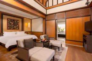 a bedroom with a bed and chairs and a tv at Banyan Tree Phuket in Bang Tao Beach