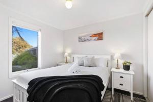 ein weißes Schlafzimmer mit einem Bett und einem Fenster in der Unterkunft Jan Juc Ocean Views - Pet friendly in Torquay