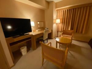 um quarto de hotel com uma secretária e uma televisão em Sabae City Hotel em Sabae