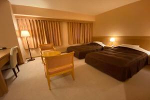鯖江市にあるサバエ・シティーホテルのベッド2台とデスクが備わるホテルルームです。