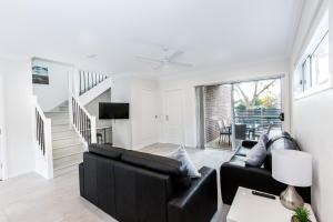 a living room with black leather furniture and a staircase at Wagga Apartments #5 in Wagga Wagga