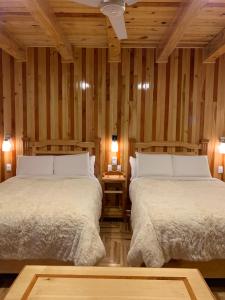 two beds in a room with wooden walls at Cabaña Zacatlan 1 in Tomatlán