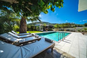 a pool with lounge chairs and a palm tree at Petronila Luxury Villa with heated private pool in Kissamos