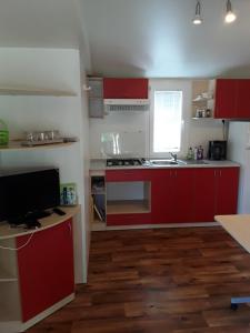 a small kitchen with red cabinets and a sink at Mobilhome Privlaka in Privlaka