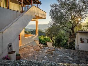 two chairs sitting on a patio with a house at Mistra Estates Villa The Vine in Pikouliánika