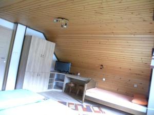 Habitación con pared de madera, escritorio y TV. en Apartma Cvetek, Srednja vas 133, en Bohinj