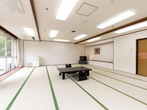 Itoen Hotel New Sakura في نيكو: غرفه فاضيه فيها طاوله بينج بونغ
