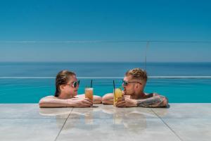 mężczyzna i kobieta siedzący w basenie z drinkami w obiekcie Villa Daniela & Apartments w mieście Koutsounari