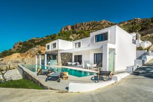 a white house with a swimming pool and a mountain at Villa Daniela & Apartments in Koutsounari
