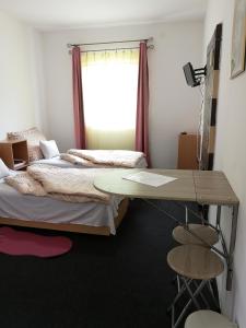 1 dormitorio con 2 camas, escritorio y ventana en Vendégház Kalocsa en Kalocsa