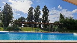 a large swimming pool with a pergola and trees at Il Casale Corte Rossa in Latina