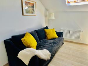 un sofá azul con almohadas amarillas en la sala de estar. en Cozy flat near Moselle Remich, en Remich