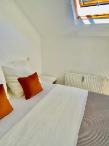 a bedroom with a white bed with orange pillows at Cozy flat near Moselle Remich in Remich