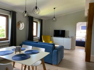 Pokoje Gościnne Cztery Wiatry في فرومبورك: غرفة معيشة مع أريكة زرقاء وطاولة