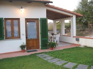 ein kleines weißes Haus mit grünen Rollläden und einer Terrasse in der Unterkunft Agriturismo Le Caselle in Cerbaia