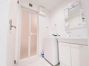 uma casa de banho branca com um chuveiro e um lavatório. em OUCHI HOTEL Hatsukaichi-Ekimae em Hatsukaichi