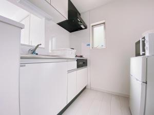 a white kitchen with white cabinets and a refrigerator at OUCHI HOTEL Hatsukaichi-Ekimae in Hatsukaichi