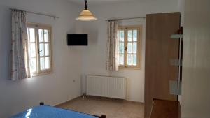 a room with a bed and two windows and a television at Chora Place in Síkinos