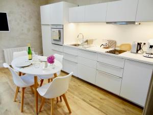 a kitchen with white cabinets and a white table and chairs at La Couette Enchantée - Parking - Zimmerbach in Zimmerbach