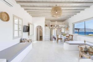 Sala de estar blanca con sofá grande y mesa en Villa Esencia, en Agios Ioannis Mykonos