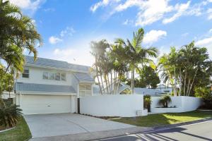Una valla blanca delante de una casa con palmeras. en Island living in the heart of Noosa, en Noosa Heads