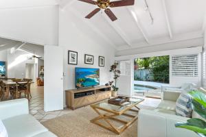 a living room with a ceiling fan and a tv at Island living in the heart of Noosa in Noosa Heads