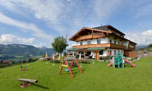 a building with playground equipment in front of a house at Alpengasthof Hirschberg in Sankt Johann in Tirol
